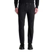 Men’s black denim straight-fit jeans with button-fly closure paired with black loafers