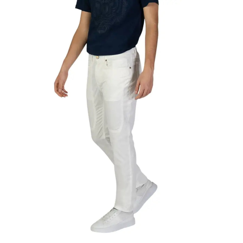 Men’s white denim jeans paired with a dark blue t-shirt and white sneakers for spring summer style