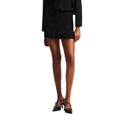 Black mini-skirt with ruffled hem, matching blazer, and pointed-toe double strap heels