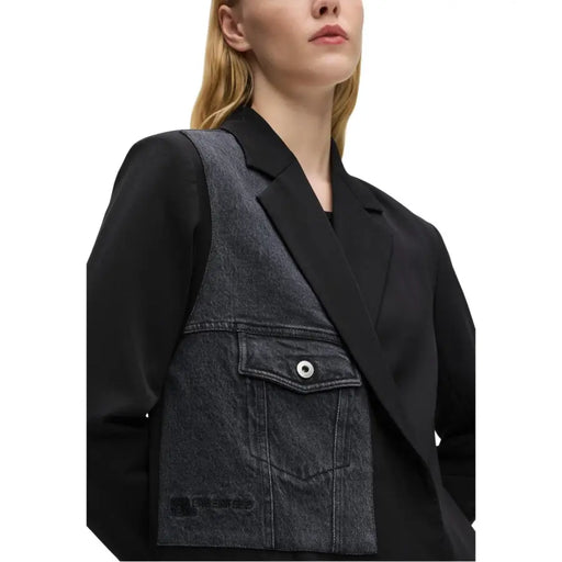 Black denim vest with silver toned button and front pocket worn over Karl Lagerfeld Jeans women’s black blazer with lapel collar