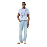 Hellblaue Jeans mit verwaschenem Look und geradem Bein, kombiniert mit einem hellblauen, kurzärmeligen Lacoste Herren-T-Shirt aus 100 % Baumwolle.
