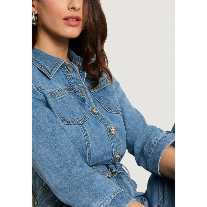 Light blue belted jumpsuit with pockets and three quarter sleeves paired with a blue denim jacket with gold buttons and collar