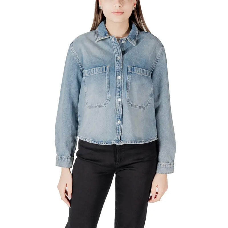 Woman wearing light-wash denim button-up shirt with front pockets, stylish classic design