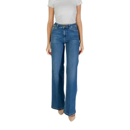 Woman wearing white short-sleeve top and flared blue Liu Jo ankle-length jeans