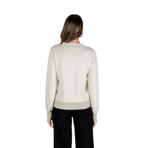 Women’s light neutral crewneck sweatshirt with ribbed hem and cuffs, paired with black wide-leg pants