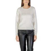 Women wearing light gray crew-neck sweater with long sleeves and black leather-look trousers