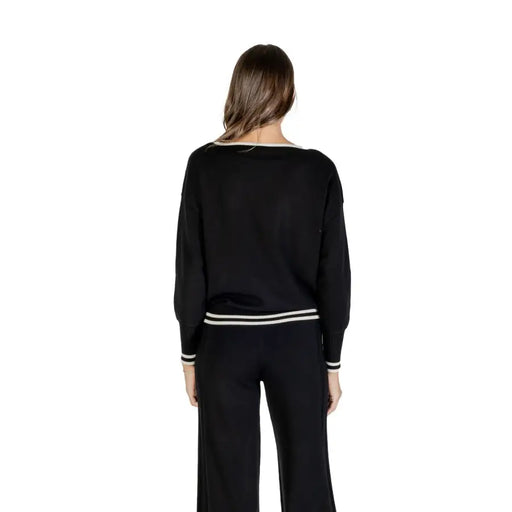 Woman wearing Liu Jo black long round neck knit sweater and pants with white stripe details