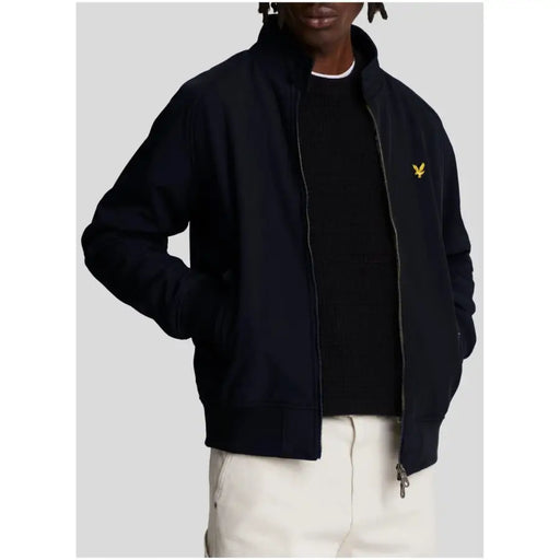Black lyle & scott bomber jacket with gold bird logo on left chest styled with men’s blue blazer with zip and pockets