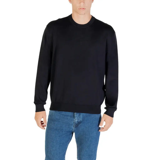 Mann in schwarzem Langarmpullover mit Rundhalsausschnitt und blauer Jeans in legerer Umgebung