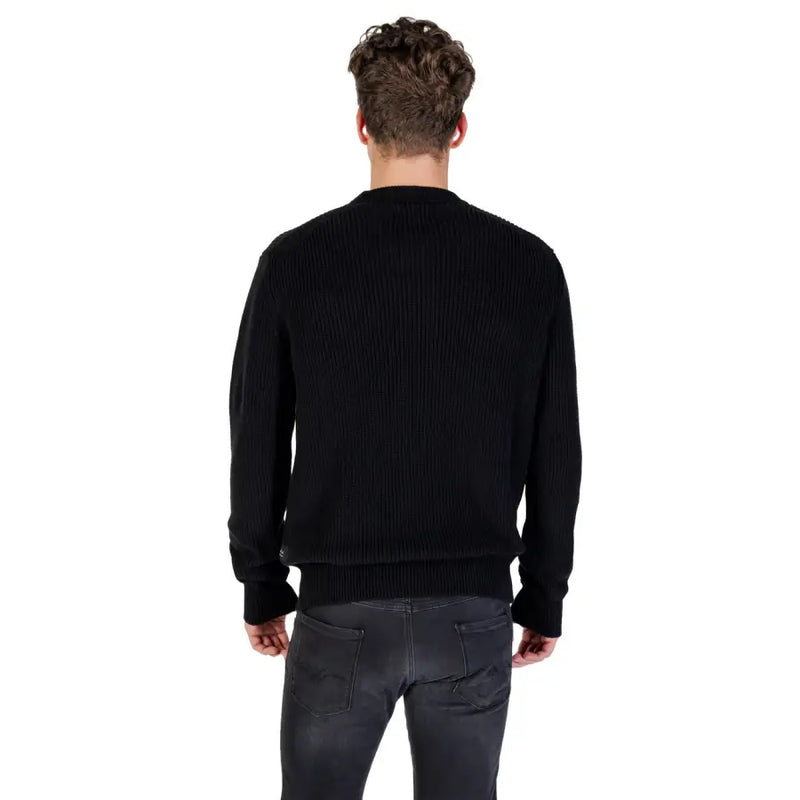 Male model wearing Black Ribbed Knit Sweater and Gray Jeans in a casual setting