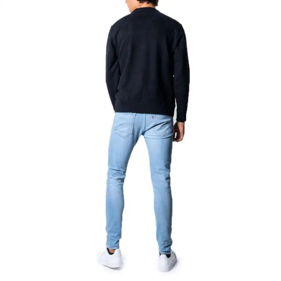 Man wearing Levi`s men sweatshirts in black, paired with jeans for casual apparel.