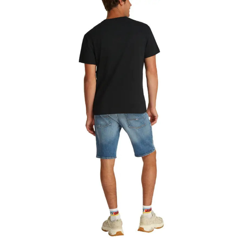 Man wearing black crewneck T shirt and blue denim shorts in a product display image