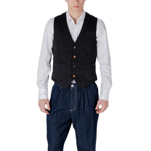 Mann in schwarzer Weste und blauer Hose, der eine marineblaue Herrenweste und ein weißes Hemd präsentiert
