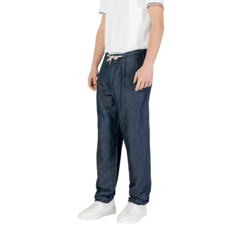 Man wearing casual blue denim drawstring pants and white shoes