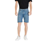 Man wearing denim shorts and white sneakers showcasing casual summer fashion