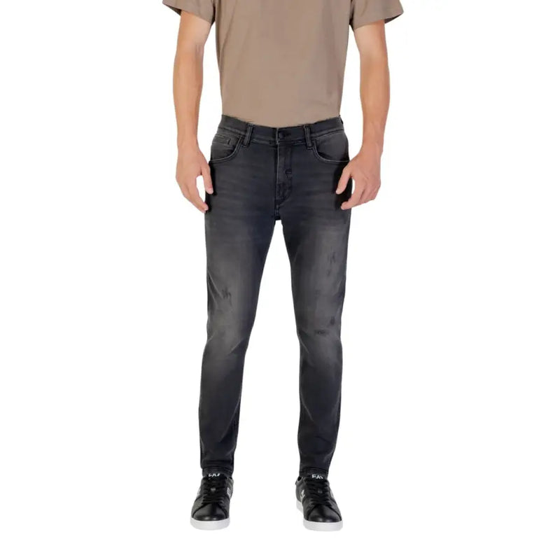 Man wearing gray slim fit jeans, tan T-shirt, and black sneakers modeling fashion style
