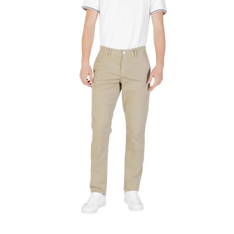 Man wearing beige trousers with zip and button closure paired with white sneakers