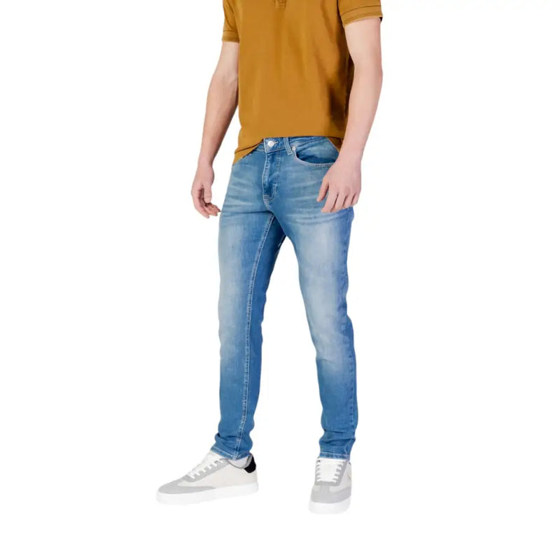 Man wearing light blue jeans and a mustard polo shirt in Men’s Jeans and Polo Shirt Collection
