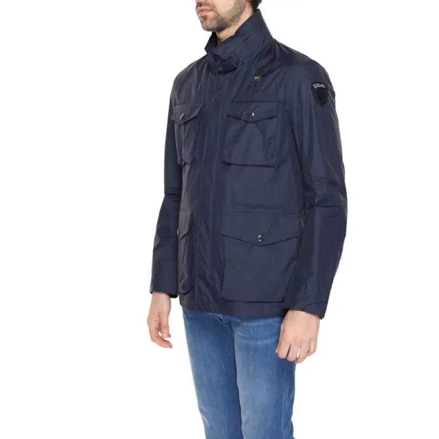 
                      
                        Man in Blauer urban style clothing, navy jacket with black hood and hat in city setting
                      
                    