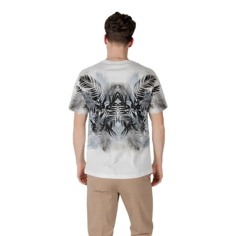 Man wearing a white T shirt with palm leaf pattern and khaki pants