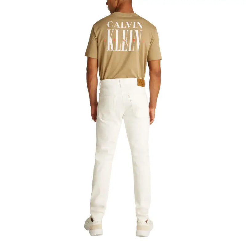 Man wearing a tan T shirt and white denim jeans offering a casual look