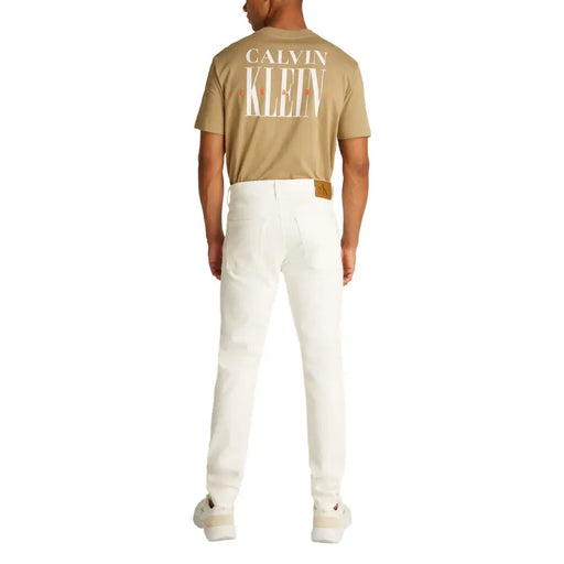 Man wearing a tan T shirt and white denim jeans offering a casual look