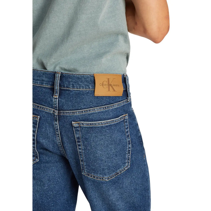 Mens blue denim shorts with tan leather calvin klein jeans logo patch on the back waistband
