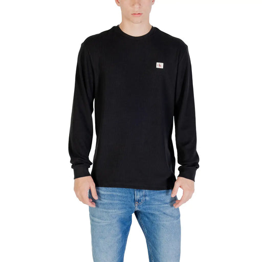 Man wearing a black long-sleeved shirt paired with blue jeans