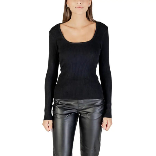 Woman wearing Morgan De Toi black long knit sweater with square neckline and leather-look pants