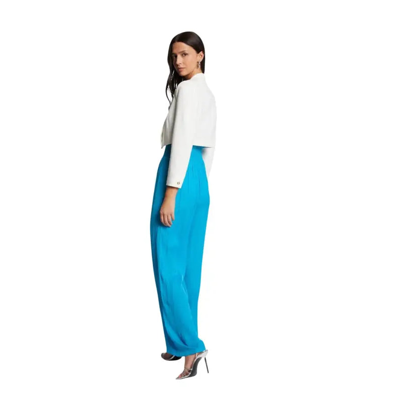 A woman wears a Morgan de Toi white long cropped blazer paired with turquoise wide-leg trousers for spring summer