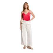 A woman wears a Morgan De Toi women coral v neck satin camisole with thin straps paired with white wide-leg trousers