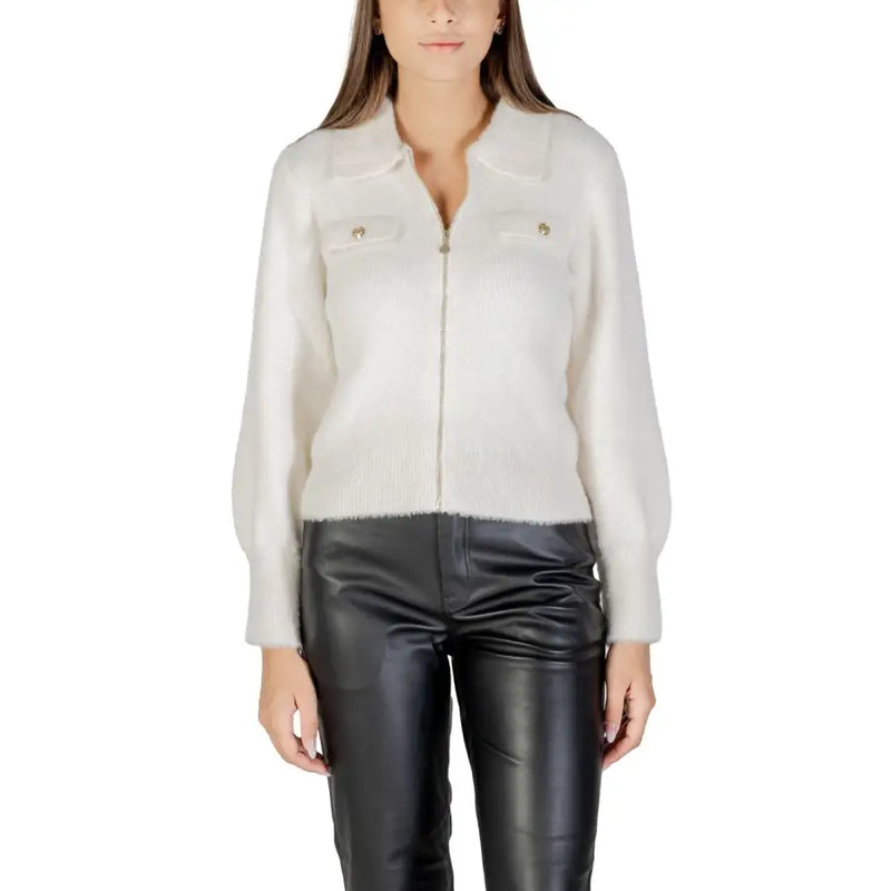 Women’s cream-colored fuzzy zip-up collared sweater with gold buttons paired with black faux leather pants