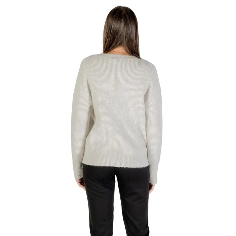 Light grey long-sleeved V neck knit sweater paired with black trousers for women
