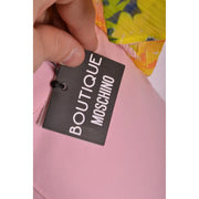 Black rectangular boutique Moschino tag with white lettering on pink Italian made women trousers for spring summer