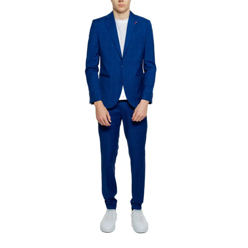 A man wearing a mulish men’s light blue suit with lapel collar in a vibrant royal blue checkered pattern paired with white sneakers