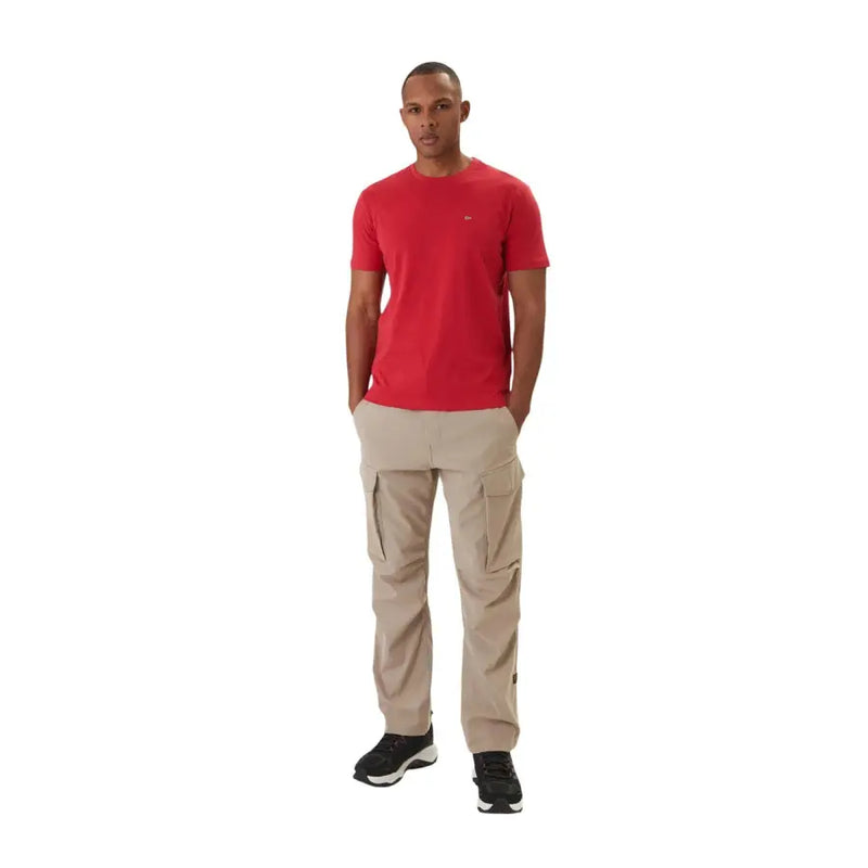 Pantalon cargo beige à multiples poches latérales et finitions discrètes napapijri logo sur la cuisse gauche associé à un t-shirt en coton rouge