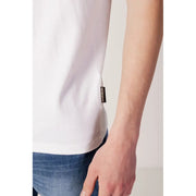 White t-shirt with gold logo and pocket detail.