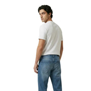 A man wearing a plain white short-sleeved cotton t-shirt and medium-wash blue denim jeans by New Balance