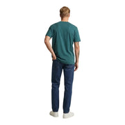 A man wearing a new balance men t shirt green cotton short sleeve round neck in teal with dark blue jeans