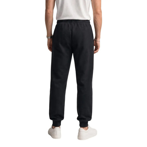 Schwarze Jogginghose aus Baumwollfleece von The North Face für Herren mit elastischem Bund und gerippten Bündchen, von hinten gesehen.