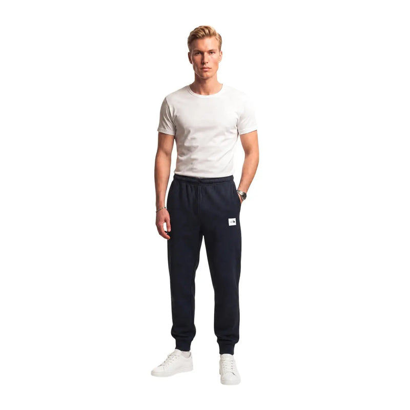 The north face men black cotton fleece trousers in navy blue feature a white logo patch and elastic cuffs