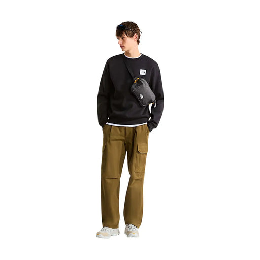 Black the north face crossbody bag with yellow zipper pull and white logo patch paired with men black cotton sweatshirt