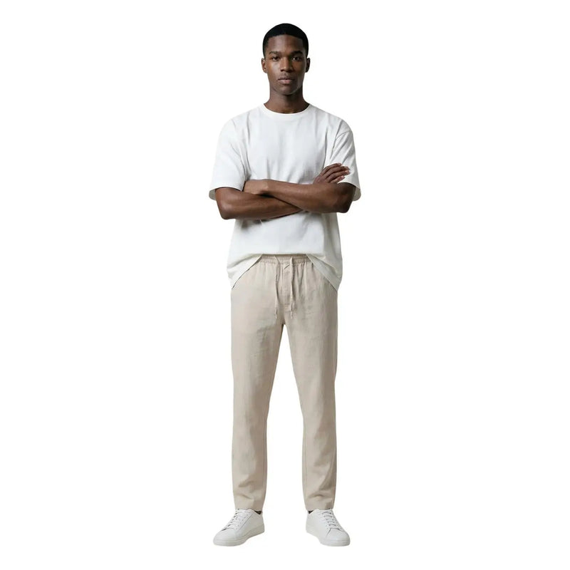 A man wearing only & sons beige drawstring trousers and a white t-shirt showcasing casual men’s pants