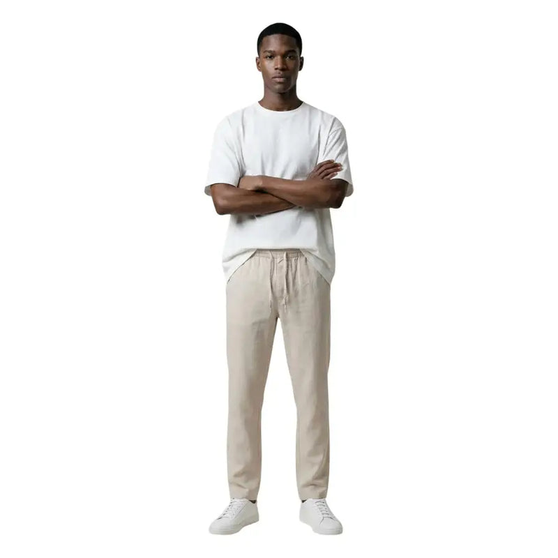 A man wearing only & sons beige drawstring trousers and a white t-shirt showcasing casual men’s pants