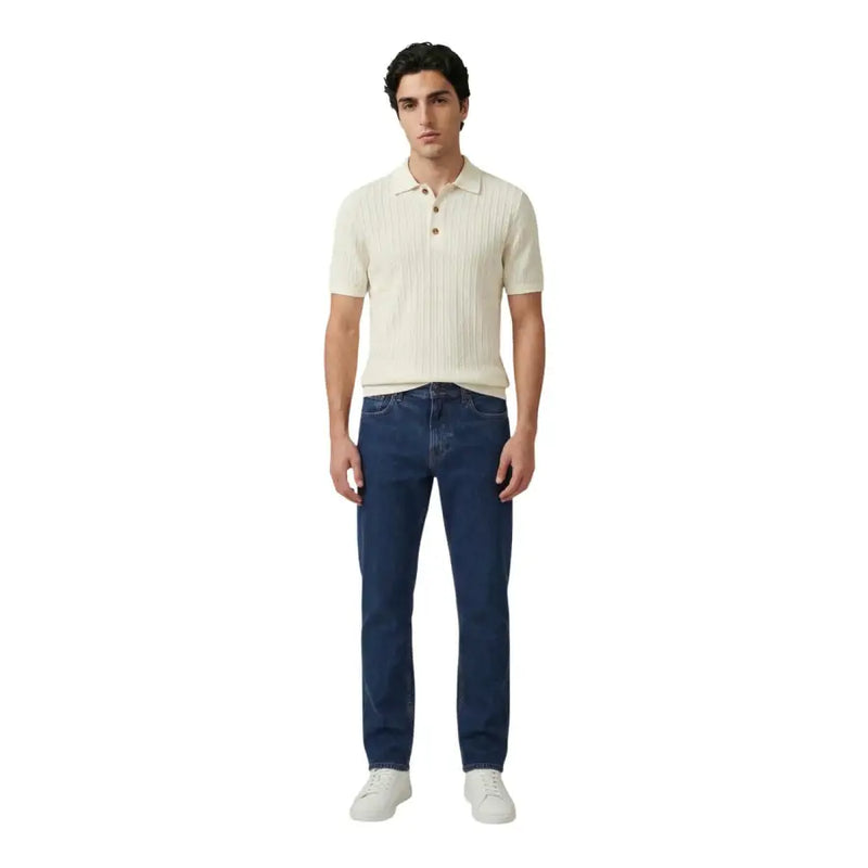 Ein Mann, der einen Only und Söhne Herren-Polohemd aus weißer Baumwolle mit kurzen Ärmeln in Creme-Rippstrick mit dunkelblauer Jeans