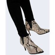 Snake-print ankle boots with sleek pointed toe and slender high heel paired with only women black cotton jeans