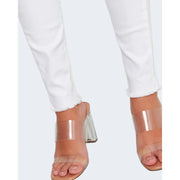 Clear acrylic block-heeled sandals with transparent straps paired with only women white cotton stretch slim fit trousers