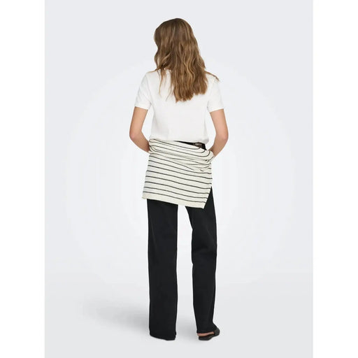 A white round neck cotton short t shirt paired with a white and black striped ribbed knit wrap skirt over dark trousers