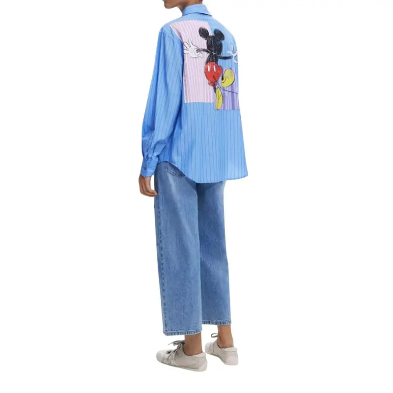 Model wearing Desigual Light Blue Classic Long Womens Shirt with Mickey Mouse graphic and light wash wide-leg jeans