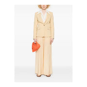 A vibrant orange fabric clutch with a structured design paired with a pinko yellow linen blazer with button front and pockets